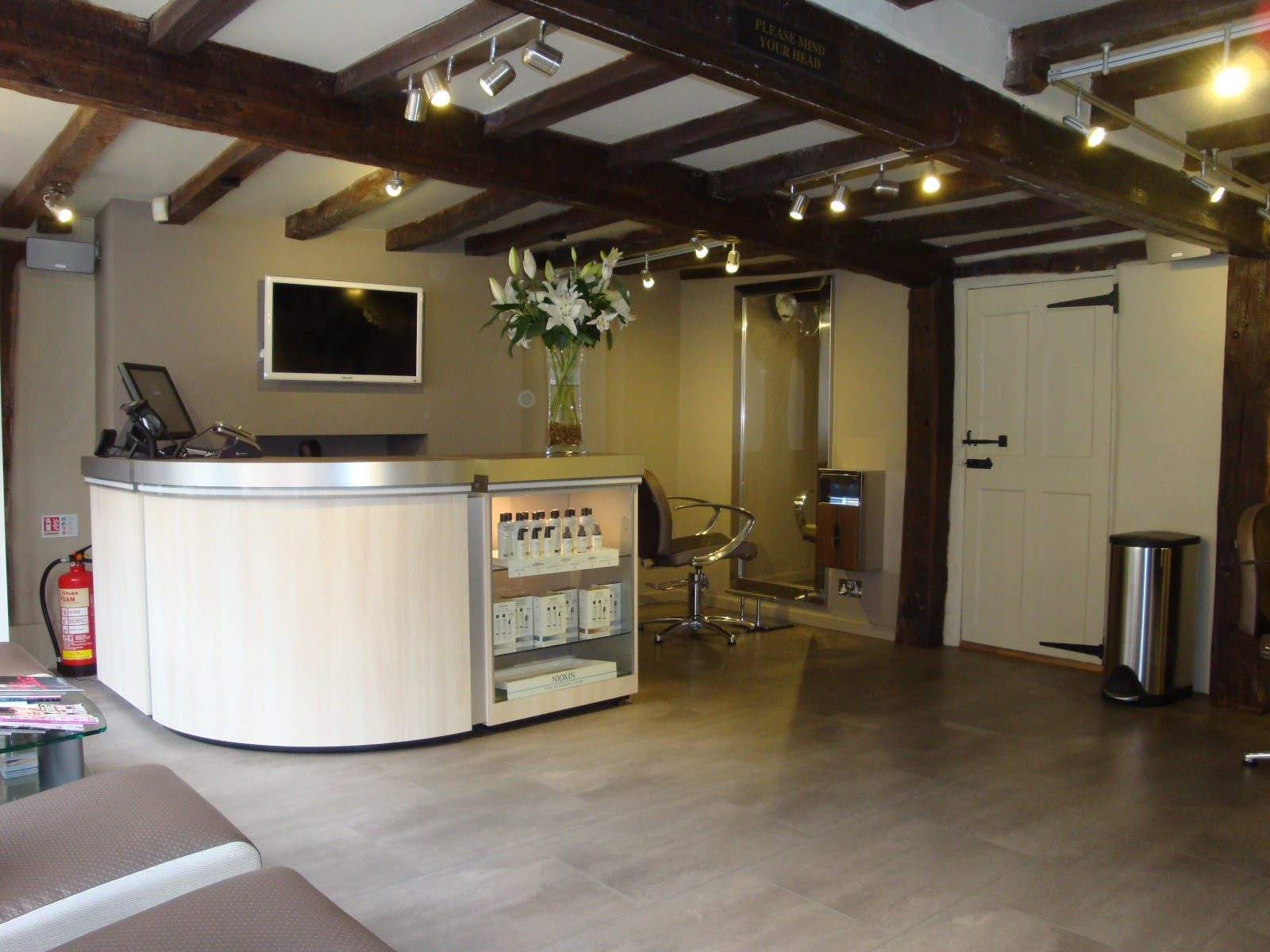 The HAIR38 salon interior on Hospital Street, Nantwich, with exposed dark timber beams and a curved pale wood reception desk